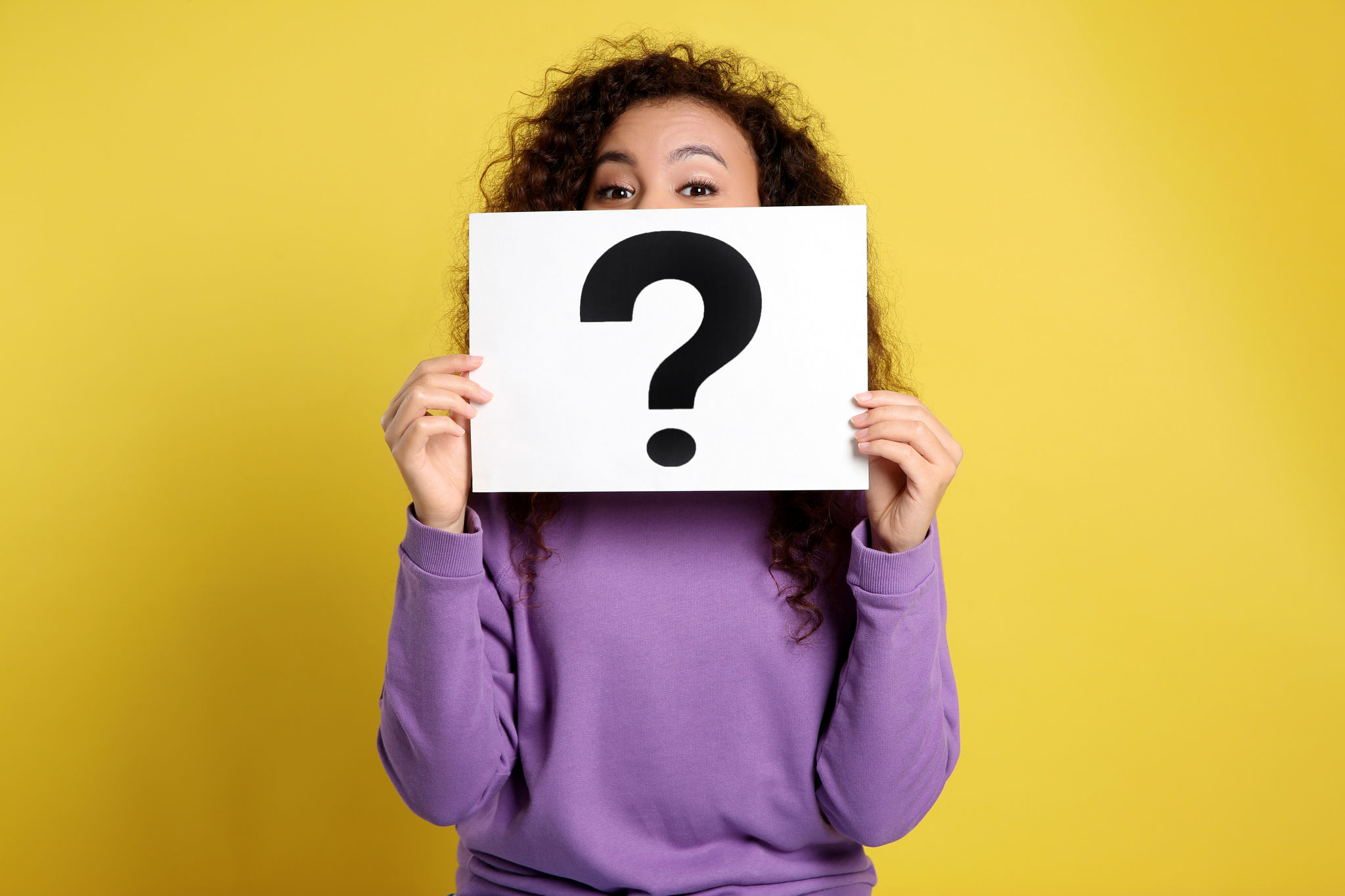 African-American woman with question mark sign on yellow background